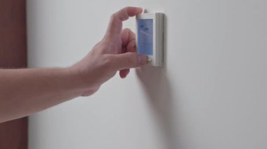 Adam klimayı açıyor ve yakın plan çekimde beyaz kumandanın ısısını düşürüyor. Yüksek kalite 4k görüntü