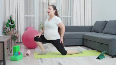 Hamile kadın, leğen kemiği dayanıklılığı, annelik uygunluğu ve esnekliği artırmak için evde esneme ve egzersiz yapıyor. Kızım, oturma odası ve doğum öncesi yoga sirkülasyon, sırt ağrısı ve duruş için. Yüksek kalite 4k görüntü