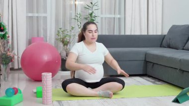 Hamile kadın, leğen kemiği dayanıklılığı, annelik uygunluğu ve esnekliği artırmak için evde esneme ve egzersiz yapıyor. Kızım, oturma odası ve doğum öncesi yoga sirkülasyon, sırt ağrısı ve duruş için. Yüksek kalite 4k görüntü