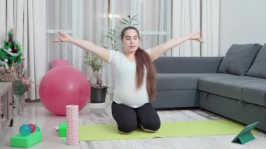 Hamile kadın, leğen kemiği dayanıklılığı, annelik uygunluğu ve esnekliği artırmak için evde esneme ve egzersiz yapıyor. Kızım, oturma odası ve doğum öncesi yoga sirkülasyon, sırt ağrısı ve duruş için. Yüksek kalite 4k görüntü