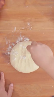Kollar hamuru un haline getiriyor. Bayan kollarının odadaki masanın üzerindeki buğday hamurunu yoğurduğu bir manzara. Yüksek kalite 4k görüntü