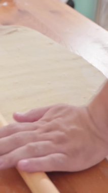 Kadın fırıncı hamuru ahşap bir masa üzerinde yuvarlıyor. Hamuru un içinde yuvarlıyor, domates ve peynirli İtalyan pizzası için hazırlıyor. Yüksek kalite 4k görüntü