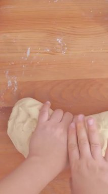 Kollar hamuru un haline getiriyor. Bayan kollarının odadaki masanın üzerindeki buğday hamurunu yoğurduğu bir manzara. Yüksek kalite 4k görüntü