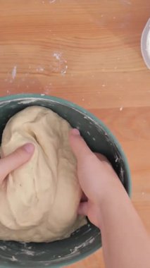 Kollar hamuru un haline getiriyor. Bayan kollarının odadaki masanın üzerindeki buğday hamurunu yoğurduğu bir manzara. Yüksek kalite 4k görüntü