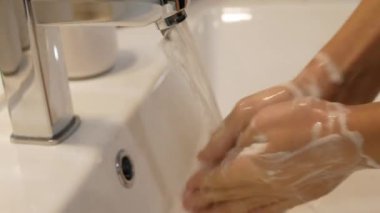 Genç çocuk ellerini sabun jeliyle yıkıyor..