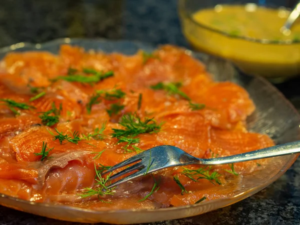 Gravlax, or gravad lax, is a Nordic dish consisting of salmon that is cured using salt, sugar, and dill. Gravlax is usually served as an appetizer, sliced thinly and accompanied by hovmastarsas, a dill and mustard sauce, either on bread or with boi