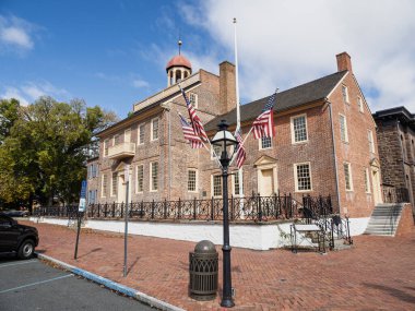 Tarihi New Castle Adliyesi Müzesi 'nin açılı bir manzarası var. Ön planda Amerikan bayrakları dalgalanıyor ve klasik bir sokak lambası var..