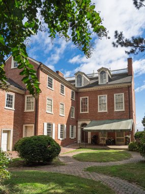 Tarihi Read House 'un yanı, beyaz pencereli büyük kırmızı tuğlalı bir bina, New Castle, Delaware' de yemyeşil yeşillikler ve mavi gökyüzü çerçeveli..