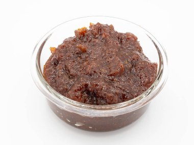 Bir porsiyon baharatlı ve keskin Hint limon turşusu (Achar veya Achaar) temiz beyaz bir arkaplanda cam bir kasede sergilenir..