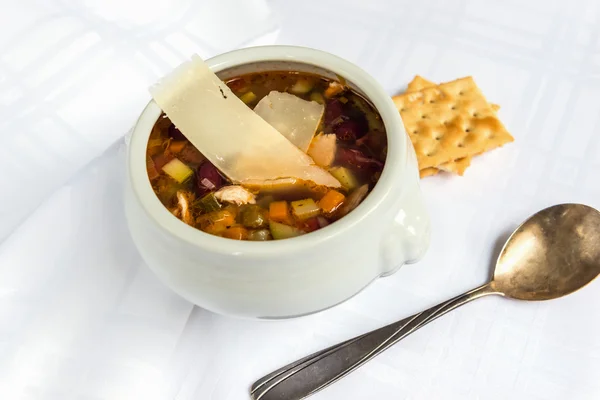 Tigela de sopa de minestrone com parmesão fatiado no fundo branco — Fotografia de Stock