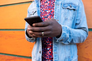 Afrika kökenli bir adamın ahşap arka planda akıllı telefon kullanması..
