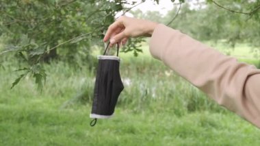 Doğada yüz maskesi tutan bir kadın. Yaklaşın, ağır çekim..