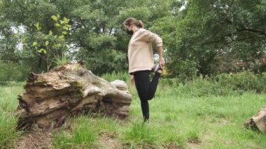 Yüzünde maske olan koşucu kadın parkta geriniyor..