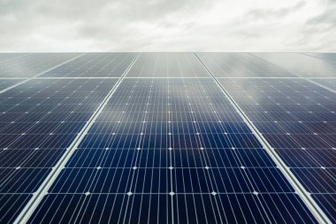 Gökyüzünde bulutlar olan güneş paneli ızgarası, alternatif güç kaynağı. Yenilenebilir enerji kavramı. Ön görünüm.
