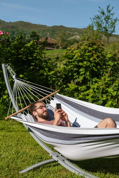 Homem Espanhol Barbudo Olhando Para Telefone Celular Deitado Rede Ambiente — Fotografia de Stock