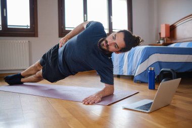 Sakallı adamın portresi çevrimiçi bir sınıfla evde antrenman yaparken yan kalas yapıyor..