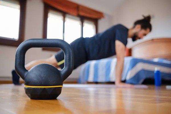 Bir erkek evde egzersiz yaparken kettlebell yakın plan çekimde. Seçici odak.
