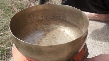 Tibet kâsesi suyla dolu. Titreşiyor ve damlaları dışarı sıçratıyor..