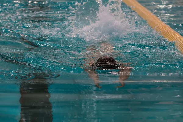 Swimmer in the pool. Freestyle swimming. Low key, dark background, spot lighting, and rich Old Masters — Stock Photo, Image