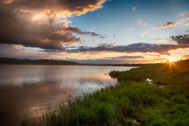 Gölde. yağmurdan sonra muhteşem gün batımı. Düşük anahtar, koyu arka plan, spot aydınlatma ve zengin eski ustalar