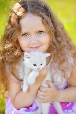 Sevimli küçük kız yaz gününde küçük yavru kedi ile oynarken