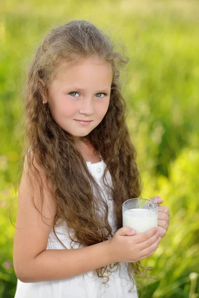 Niña linda bebiendo un vaso de leche al aire libre verano — Foto de Stock
