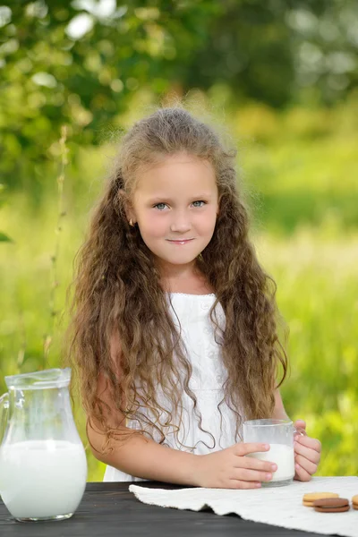 Niña linda bebiendo un vaso de leche al aire libre verano — Foto de Stock