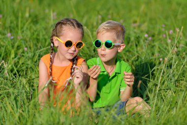 Mutlu arkadaşlar açık havada çim eğleniyor güneş gözlüğü.