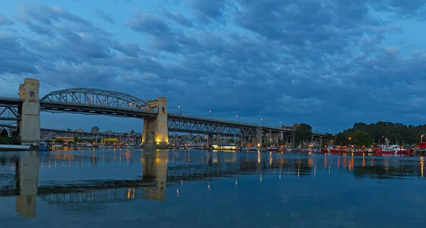 Vancouver city skylike with bridge at dawn,Bbritish Columbia, Canada. Urban landcape at dawn with sailboats, historic bridge and reflections in water.