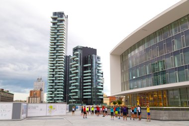 MILAN, ITALY - JULY 8, 2014: People stretching and doing morning exercise on Plaza Gae Aulenti in Milan, Italy on July 8, 2014.