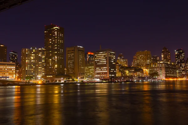 Manhattan skyscrapers with colorful reflections in East River at night. — Stock Photo, Image