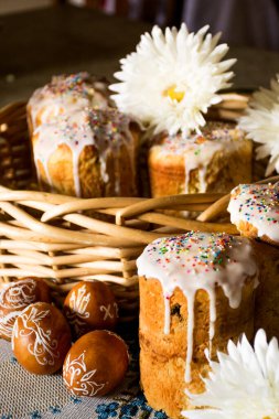 Boyanmış yumurtalarla dolu sepet, beyaz çiçeklerle dolu sepetli Paskalya ekmeği. Paskalya yumurtalı Paskalya sepeti