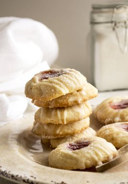 Beyaz arka planda çilek reçeli dolu parmak izi kurabiyeleri. Çilek reçelli bir yığın kurabiye.