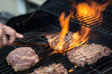 grilling steaks on flaming grill. Cooking outside concept  clipart