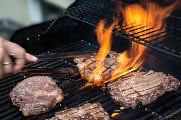 Grilling steaks on flaming grill. Cooking outside concept — Fotografia de Stock