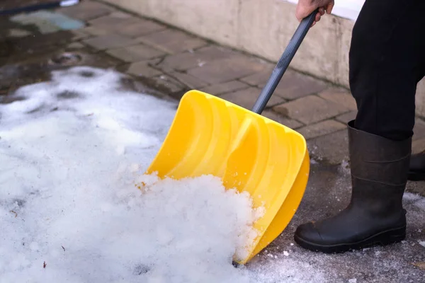 Человек с лопатой очищает тротуар зимой. Зимнее время. — стоковое фото