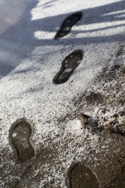 Ślady stóp w topniejącym śniegu. Tekstura śniegu z odciskami butów. — Zdjęcie stockowe