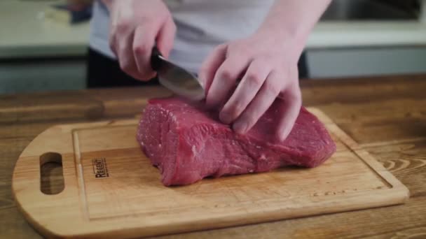 Carne de corte sobre una tabla de cocina de madera. — Stockvideo