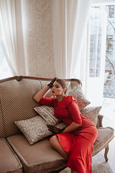 woman posing in vintage interior. lady wearing red dress and black gloves. beautiful brunette