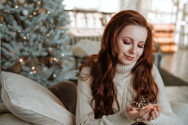 Noel portresi. Parti, tatil ve kutlama konsepti. Elinde Noel süsleri tutan gülümseyen kadının yakın çekimi. Festival odasında tatil hazırlığı. Kış tatili için dekor