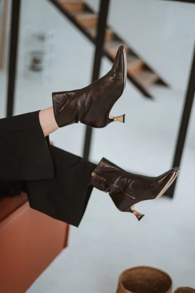 legs of a girl in black leather boots on a light bright background. fashion photography fashionable lookbook new shoe collection autumn winter