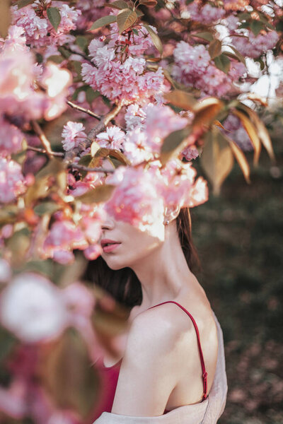 Creative artistic portrait in cherry blossom. beautiful woman near blooming tree.
