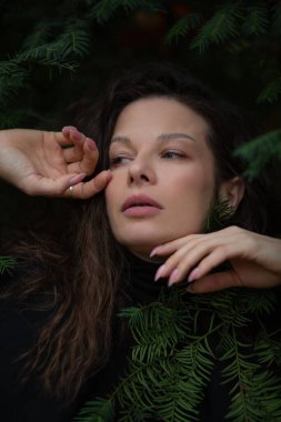 Alacakaranlıktaki mistik bir ormanda, yakın plan bir kadın portresi. Yüzündeki ifade gizemlidir, yumuşak bir ışık gölgelerin arasında yüzlerini aydınlatır..