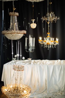 Beyaz masa örtüsünün üzerinde çeşitli avizeler asılı.