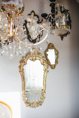 Zarif avizelerin yanında asılı duran süslü aynalar.