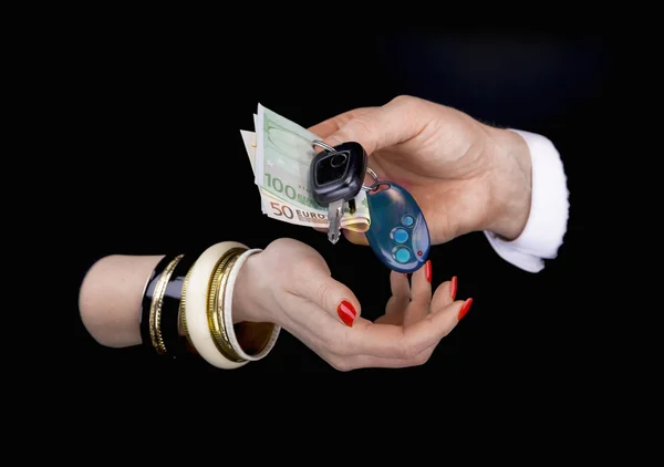 Men's hand giving to  woman's hand eurobanknotes and car keys — Stock Photo, Image