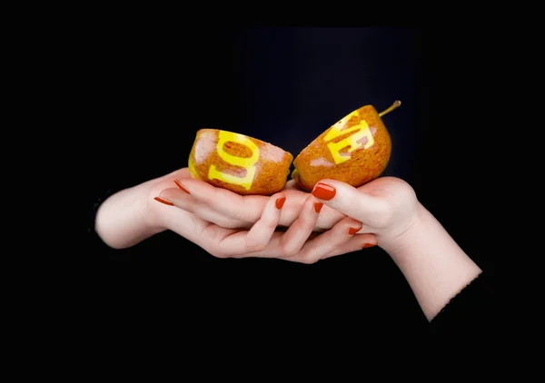 Two pieces of an apple with separated word love on a women's han — Stock Photo, Image