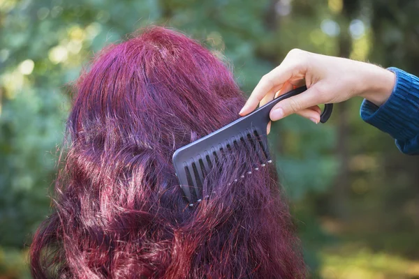 Girl's hand with black comb combing woman's red hair — Stock Photo, Image