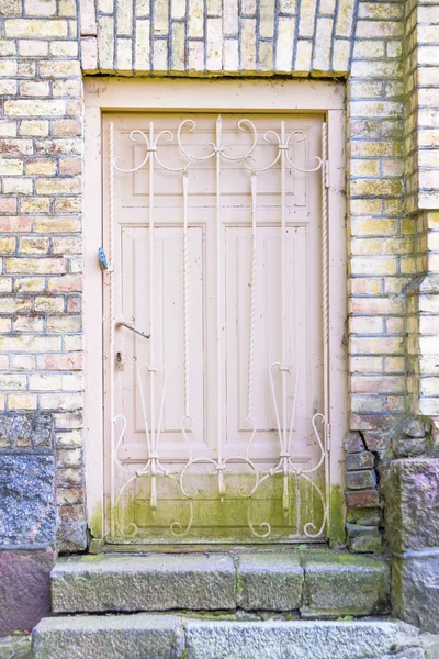 Alte Holztür mit Gitter in einer Ziegelwand — Stockfoto