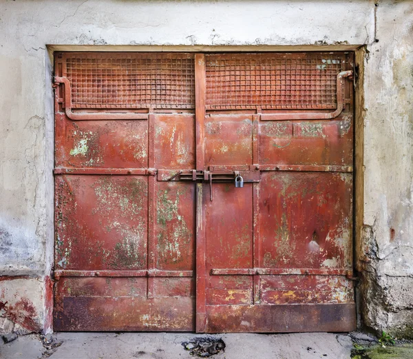 Cadeado de metal em um metal vermelho antigos portões de garagem — Fotografia de Stock